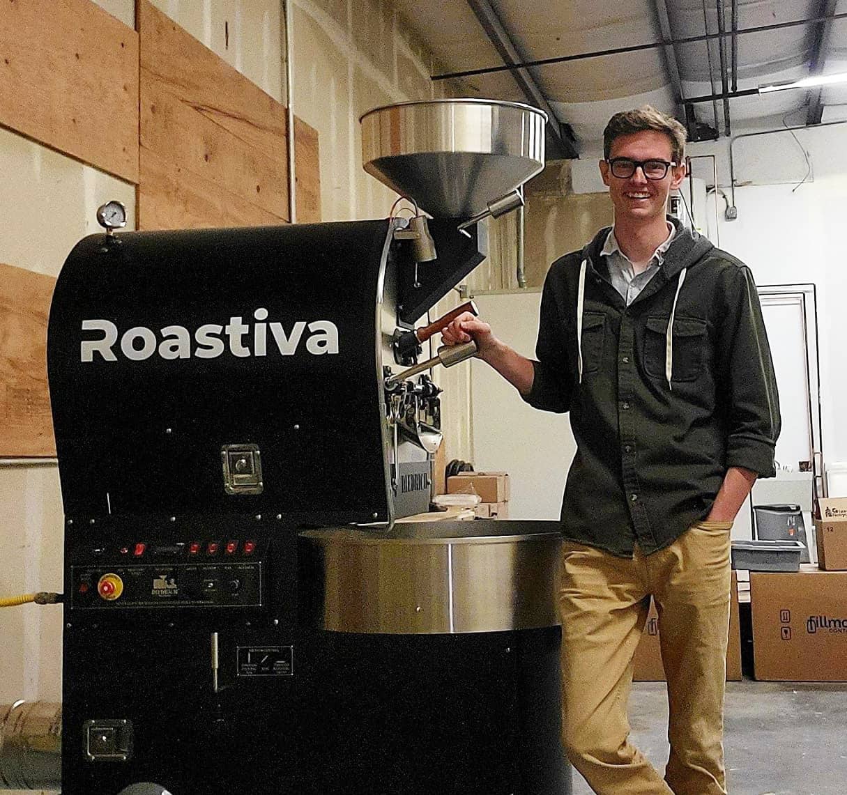 Josiah Abshear standing beside a black Roastiva coffee roaster